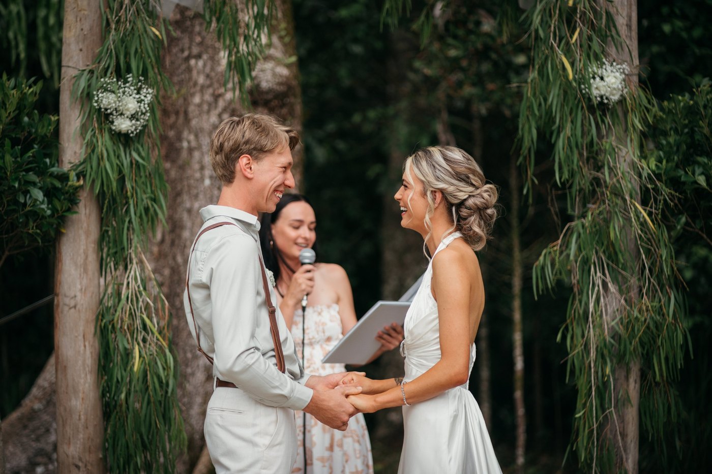 A couple laughing and holding hands during an outdoor wedding ceremony